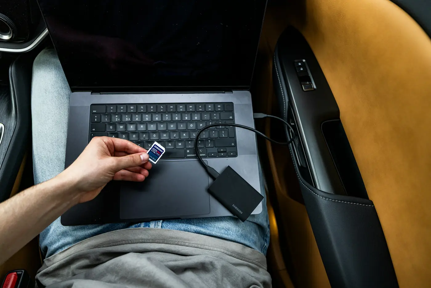 OBD reader plugged into a laptop on the driver's seat, reading fault codes