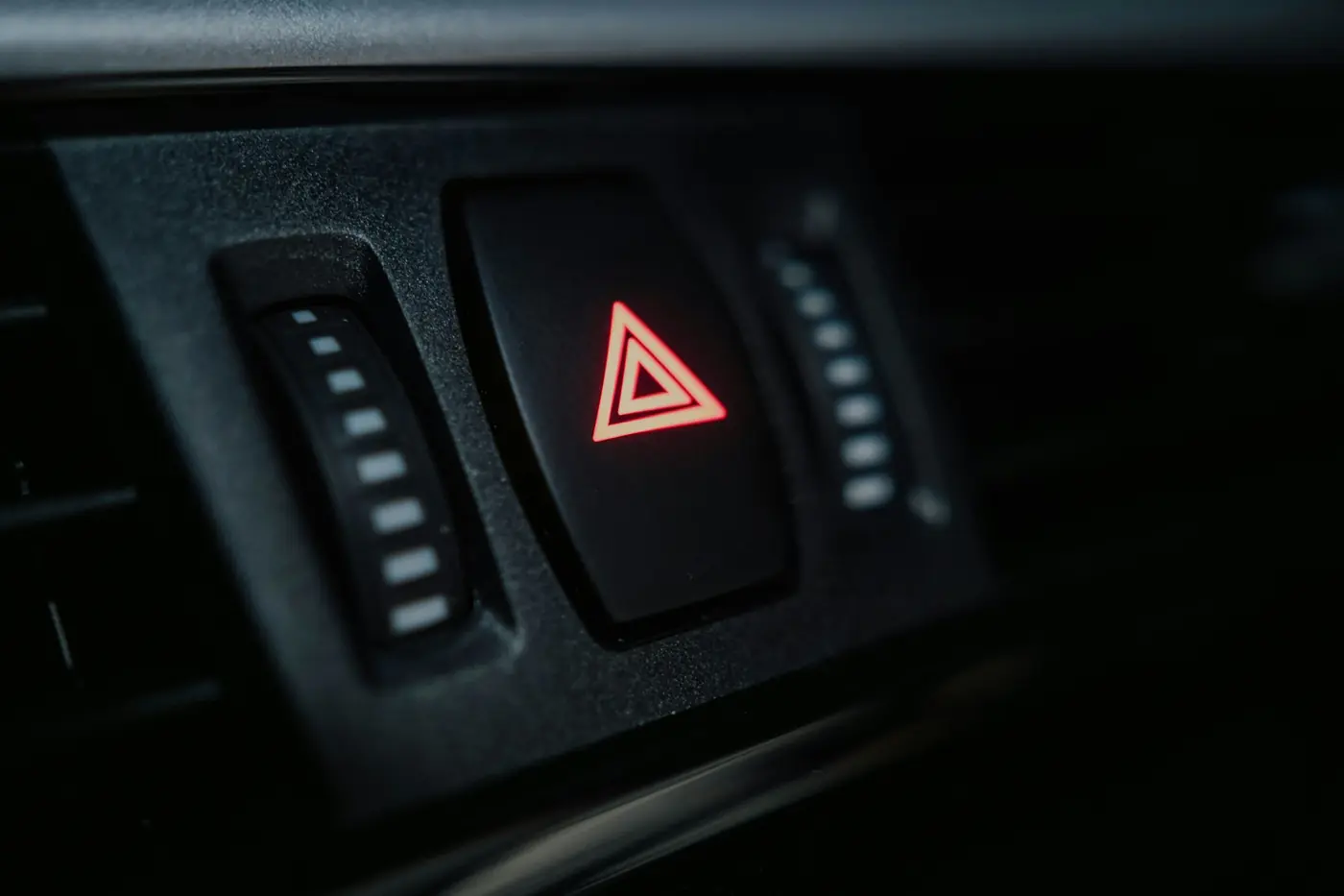 Hazard light switch lit on a car dashboard