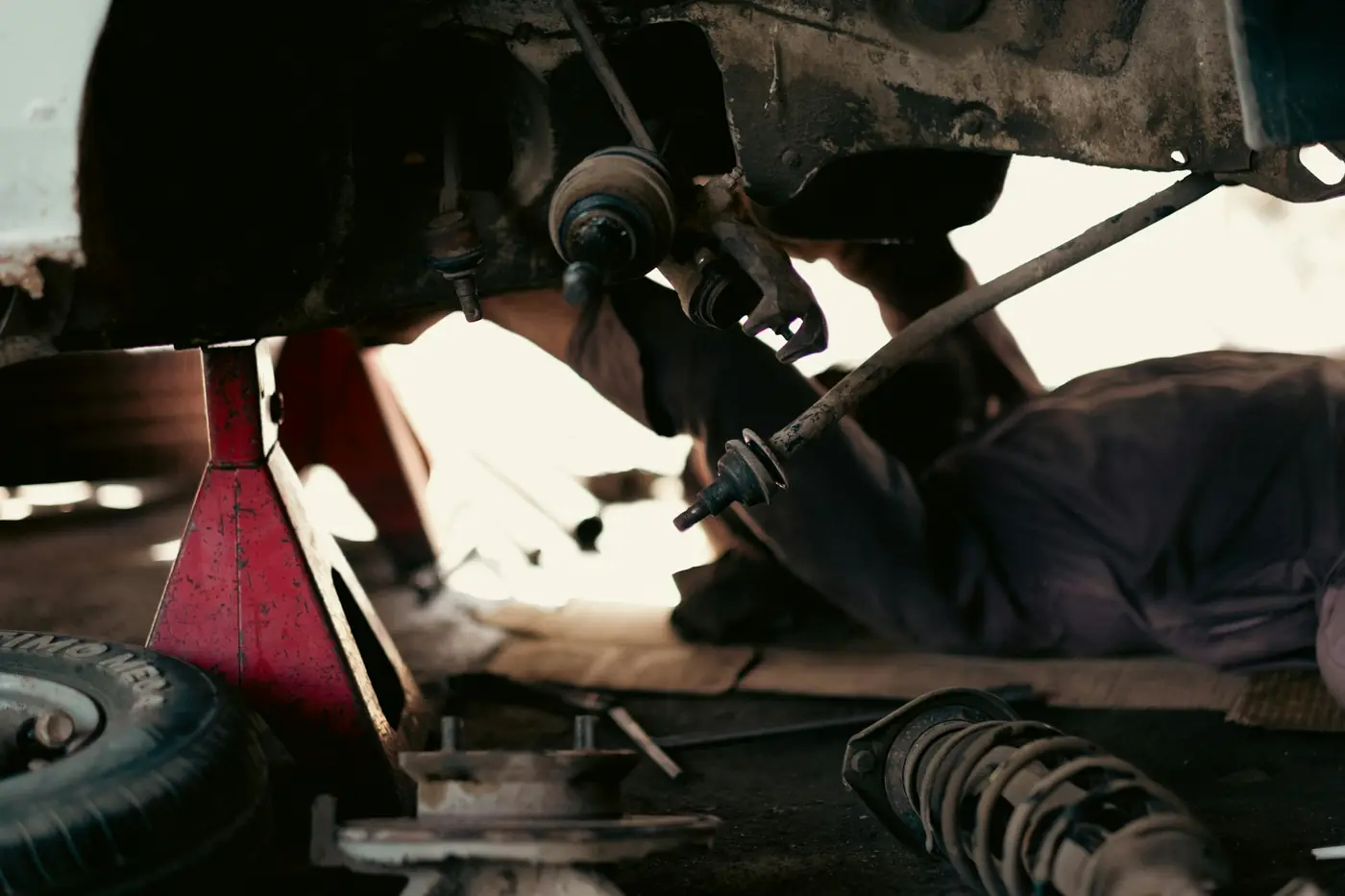 Mechanic working under a car on the hoist, replacing a suspension component